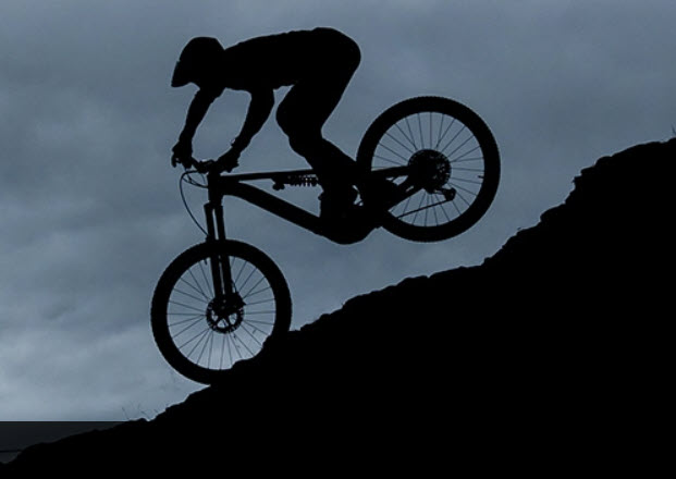 Downhill mountain biker descending a steep rocky slope